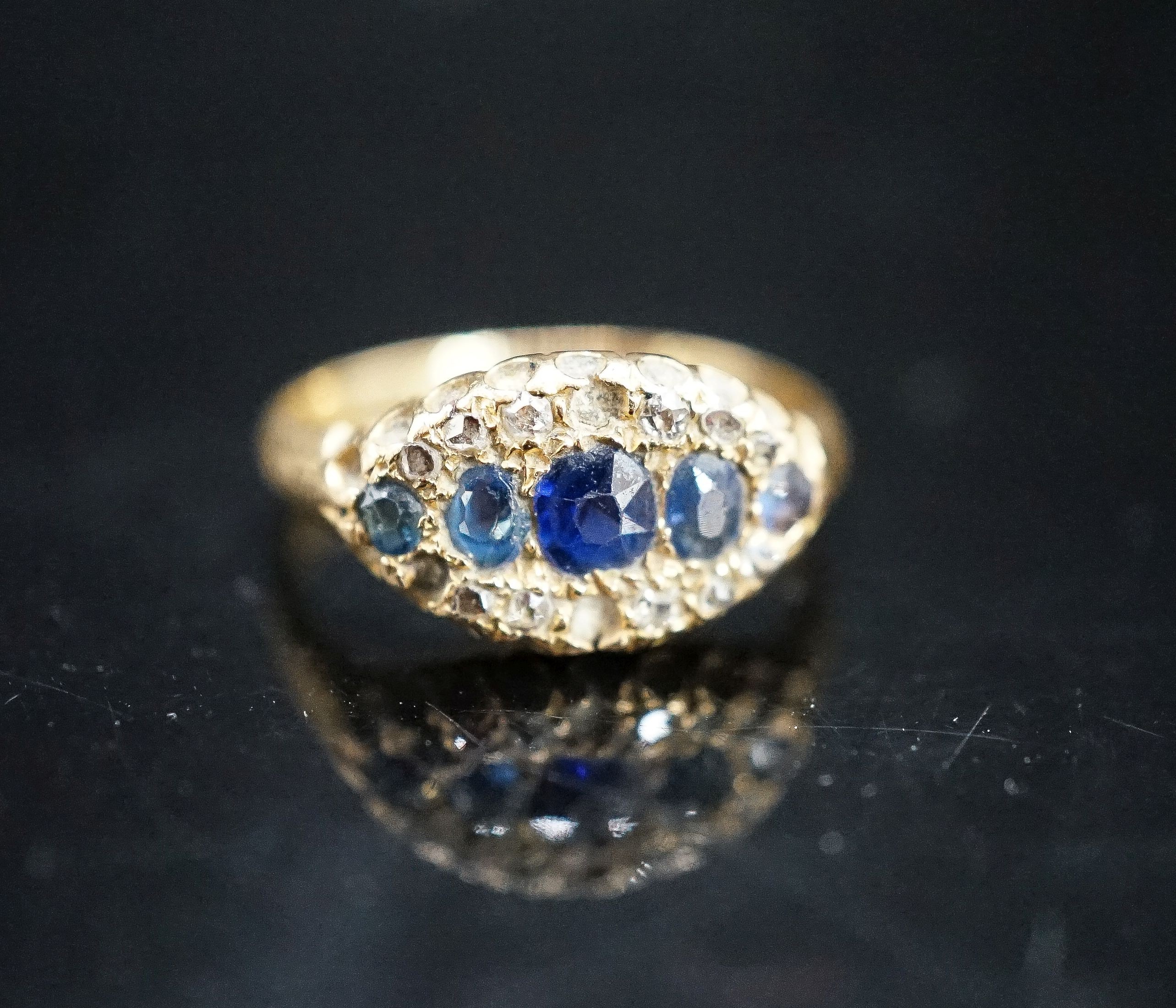 An early 20th century 18ct gold, graduated five stone sapphire and rose cut diamond set cluster ring, size J/K, gross weight 3.3 grams.